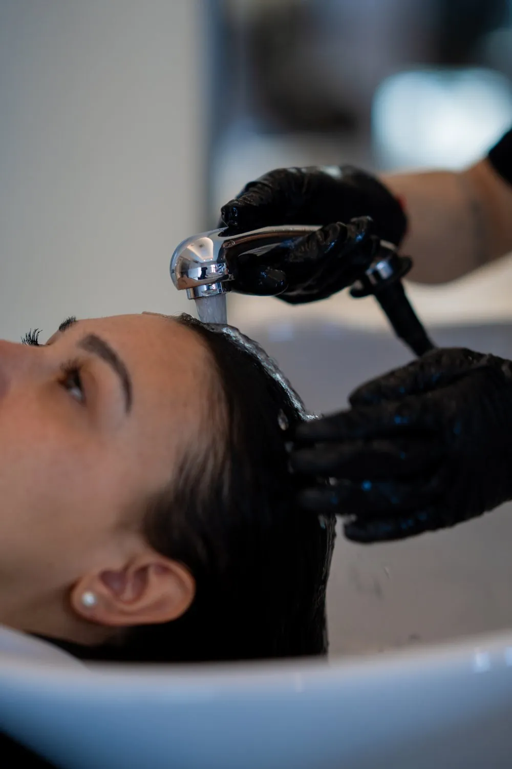 Lavaggio capelli al lavandino con guanti professionali